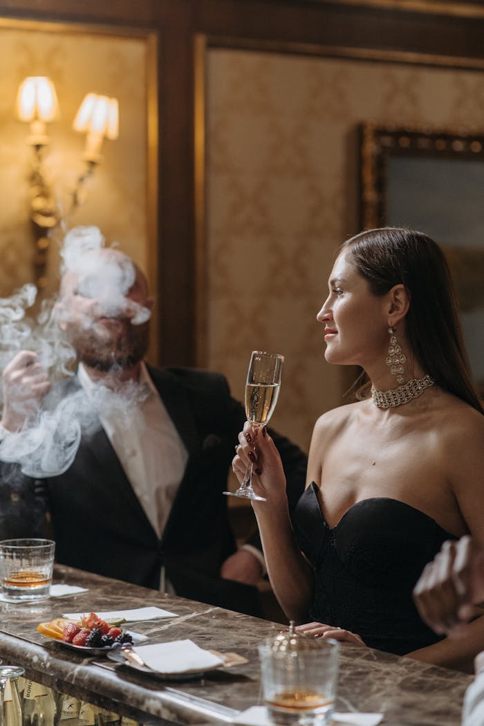 A sophisticated couple in formal attire enjoying champagne at a classy bar setting.